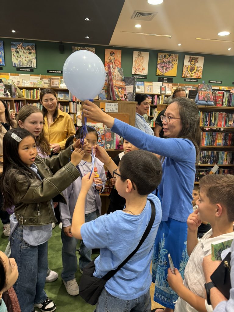 Author brings a balloon with ribbons tied to it to the crowd of children and lets them count the ribbons